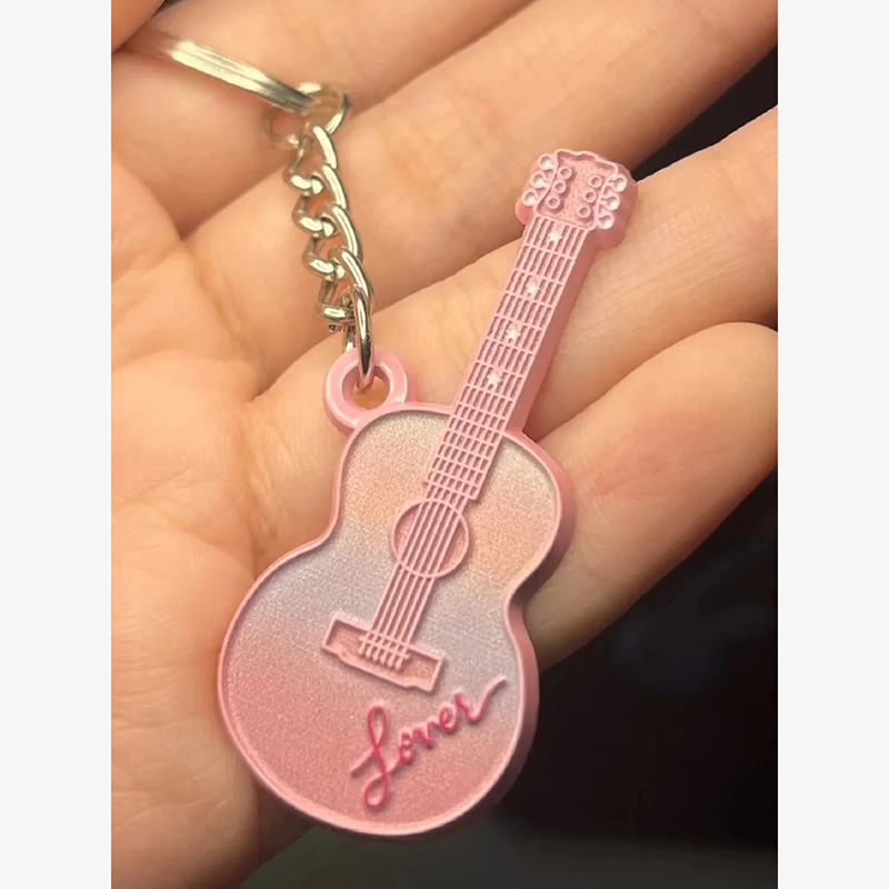 Llavero de guitarra de color rosa con la inscripción "Lover